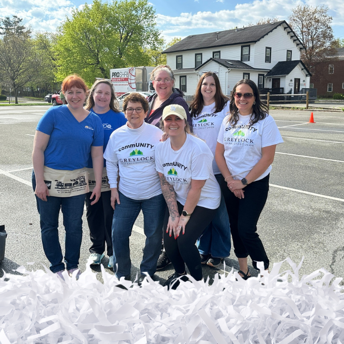 A group of volunteers in t-shirts pose together in a parking lot