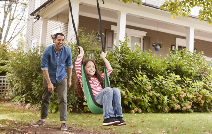 dad pushing daughter on swing